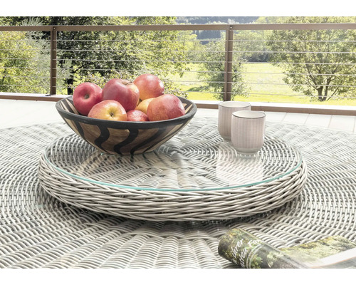 Heller drehbarer Tablettaufsatz aus grauem Kunststoffgeflecht mit Glasplatte auf einem runden Gartentisch mit Obstschale und Tassen im Freien.