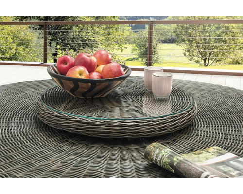 Runder Gartentisch aus grauem Polyrattan-Geflecht mit Glasplatte, darauf eine Obstschale und Tassen auf einer Terrasse mit Geländer und Naturblick.