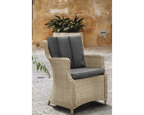 Gartensessel aus Geflecht mit Sitz- und Rückenkissen auf einer Terrasse im Außenbereich.