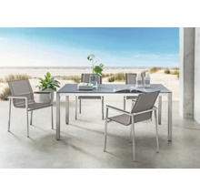 Moderne Gartenmöbelgruppe mit rechteckigem Esstisch und vier Stühlen auf einer Terrasse mit Strandblick. Tisch mit dunkler Platte und Metallgestell.