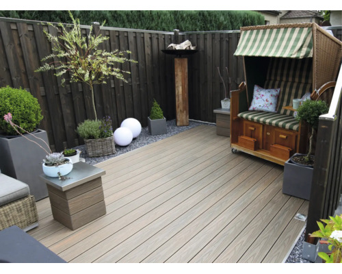 Moderne Terrasse mit Terrassendielen aus Holz-Kunststoff-Verbundwerkstoff, einem hölzernen Sichtschutzzaun, einem Strandkorb und Pflanzgefäßen.