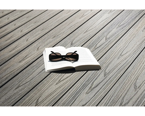 Terrassendielen in Holzoptik mit einem aufgeschlagenen Buch und einer Sonnenbrille darauf.