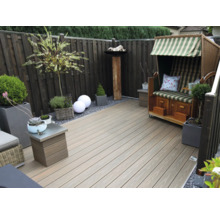 Moderne Terrasse mit Terrassendielen aus Holz-Kunststoff-Verbundwerkstoff, einem hölzernen Sichtschutzzaun, einem Strandkorb und Pflanzgefäßen.