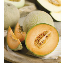 Ganze und aufgeschnittene Cantaloupe-Melone mit orangefarbenem Fruchtfleisch und Kernen auf einem Holzteller.