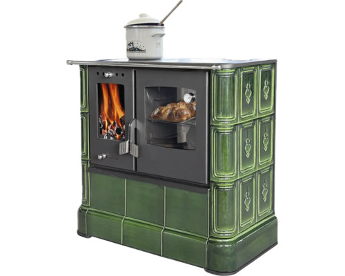 Holzherd mit grüner Kachelverkleidung, Brennkammer mit Feuer, Backfach mit Gebäck und Kochtopf auf der Kochfläche.