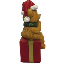 Weihnachtsfigur Bär mit Weihnachtsmütze und Schal, sitzend auf einem roten Geschenkpaket.