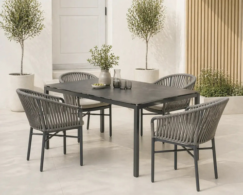 Moderne Garten-Essgruppe mit dunklem rechteckigem Tisch und grauen Seilflechtstühlen mit hellen Kissen auf einer hellen, organisierten Terrasse.