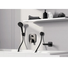 Modernes Badezimmer mit schwarzer Unterputz-Badewannenarmatur, Handbrause und Wanneneinlauf an einer weißen Fliesenwand mit Regal.