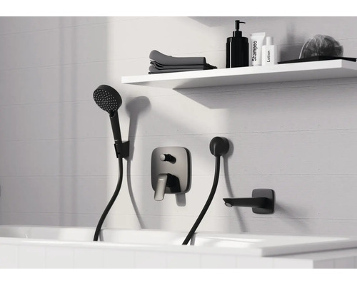 Modernes Badezimmer mit schwarzer Unterputz-Badewannenarmatur, Handbrause und Wanneneinlauf an einer weißen Fliesenwand mit Regal.