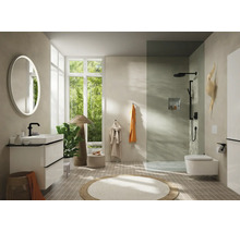 Helles, modernes Badezimmer mit weißem Waschtisch, schwarzer Armatur, rundem Leuchtspiegel, begehbarer Dusche mit Glaswand und Wand-WC.