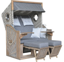 Grauer Strandkorb aus Holz und Geflecht mit zwei Fußstützen, Kissen und klappbaren Tischen.