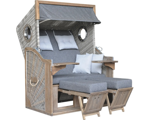 Grauer Strandkorb aus Holz und Geflecht mit zwei Fußstützen, Kissen und klappbaren Tischen.