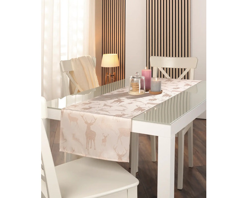Tischläufer mit glitzernden Hirschmotiven auf einem weißen Glastisch in einem hellen, modernen Esszimmer.
