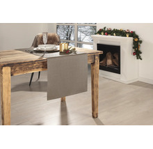 Strukturierter Tischläufer auf einem rustikalen Holztisch in einem festlich dekorierten Raum mit Kamin und Weihnachtsdekoration.