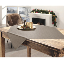 Glitzernde Mitteldecke auf einem Holztisch in einem hellen, winterlich dekorierten Raum mit Kamin und Weihnachtsguirlande.