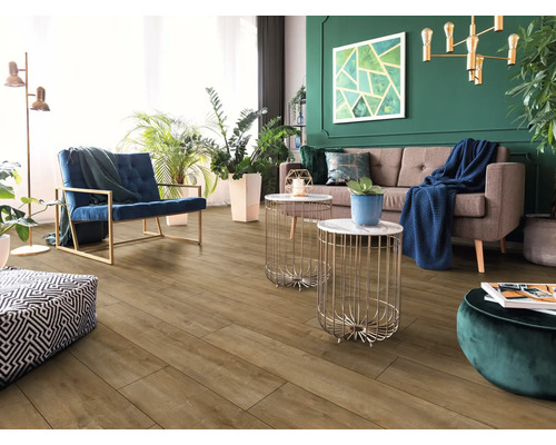 Modernes Wohnzimmer mit Bodenbelag in Holzoptik, braunem Sofa, blauem Sessel, goldenen Beistelltischen und grüner Wand mit Zimmerpflanzen.