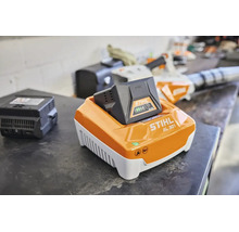 STIHL Schnellladegerät AL 301 mit eingesetztem Akku AK 30 auf einer Werkbank in einer Werkstatt.