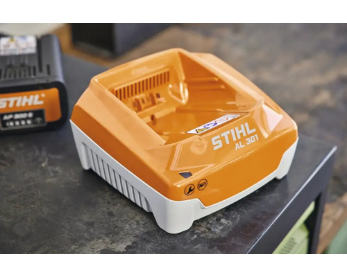 STIHL Schnellladegerät AL 301 mit Wartungs- und Ladestatusanzeige auf einer Arbeitsplatte.