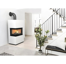 Weißer Kaminofen mit L-förmiger Sichtscheibe und brennendem Feuer in hellem Wohnbereich neben einer Treppe.