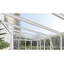 Weiße Terrassenüberdachung aus Aluminium mit lichtdurchlässigen Hohlkammerplatten und Seitenelementen aus Glas vor einer Natursteinwand.
