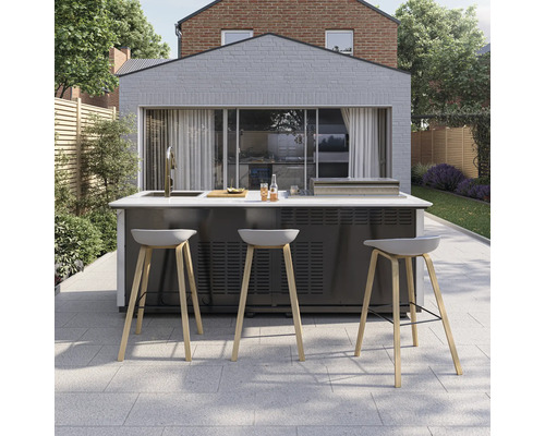 Moderne Außenküche auf gepflasterter Terrasse mit Grill, Spülbecken und Barhockern mit Holzbeinen vor einem Gartenhaus.