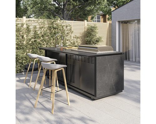Moderne Outdoor-Kücheninsel mit Spülbecken, Grill und drei Barhockern auf einer gefliesten Terrasse vor einem Holzzaun.