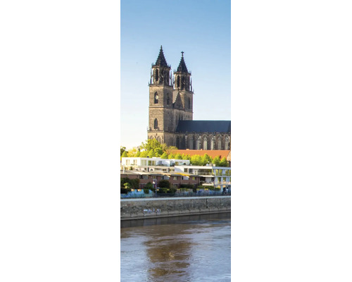 Blick auf den Magdeburger Dom hinter modernen Wohngebäuden am Flussufer der Elbe.