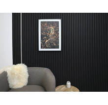 Moderne Wandgestaltung mit schwarzen Akustikpaneelen aus Holzlamellen in einem organisierten Wohnzimmer mit grauem Sessel und Holztisch.