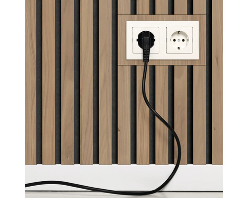 In Holzlamellenpaneel integrierte Doppelsteckdose mit passendem Rahmen und eingestecktem Stecker.