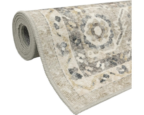 Teilweise aufgerollter Teppich im Vintage-Stil mit orientalischem Ornament-Muster und umlaufender Kettelung.