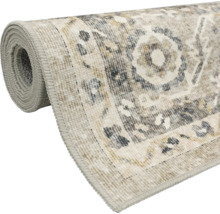 Aufgerollter Teppich im Vintage-Stil mit Medaillon-Muster und geketteltem Rand in Beige und Grau.