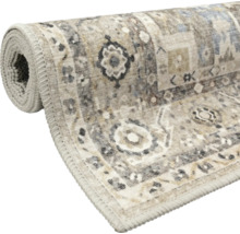Aufgerollter Kurzflorteppich mit orientalischem Vintage-Muster in Beige und Grau sowie einer gekettelten Kante.