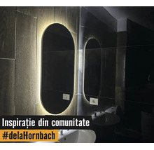 Moderner ovaler Badezimmerspiegel mit LED-Hintergrundbeleuchtung an einer Wand in Holzoptik über einem weißen Waschbecken.