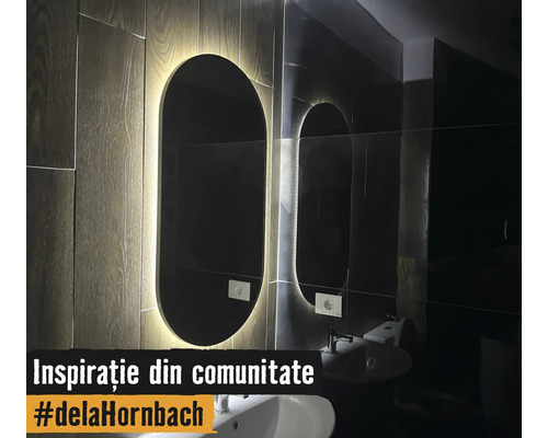Moderner ovaler Badezimmerspiegel mit LED-Hintergrundbeleuchtung an einer Wand in Holzoptik über einem weißen Waschbecken.