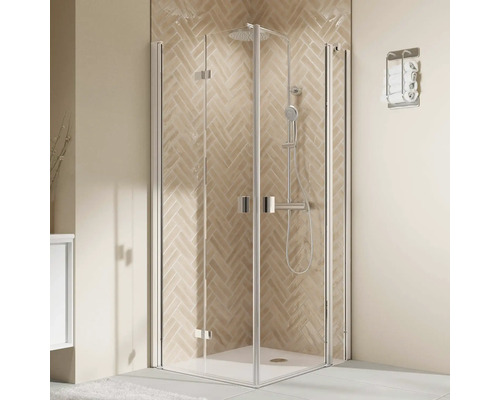 Eckduschkabine mit Falttüren und Duschsystem vor einer Wand mit Fischgrätenfliesen in einem modern eingerichteten Badezimmer.