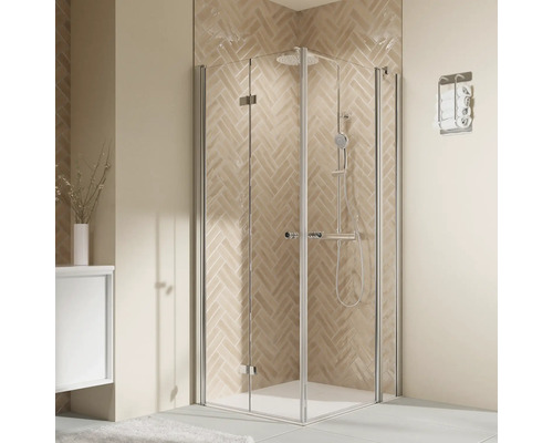 Moderne Eckduschkabine mit Echtglas und Metallprofilen in einem gefliesten Badezimmer mit Fischgrätmuster an der Wand.