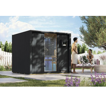 Moderne Garten-Sauna in einem Garten mit einem Paar, das vor der Sauna entspannt. Saunahaus aus Holz mit Glasfront und Steuerungselement.