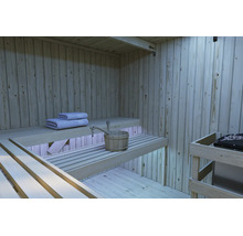 Innenansicht einer modernen Holzsauna mit abgestuften Saunabänken, Saunakübel und Handtüchern sowie einem Saunaofen.