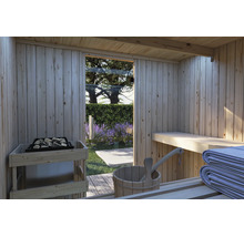 Blick aus einer finnischen Holzsauna in den Garten mit Blick auf blühende Lavendelbüsche und eine Glasfront mit Saunaofen und Holzeimer.