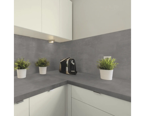 Moderne Küche mit grauer Arbeitsplatte und passendem Fliesenspiegel in Betonoptik, dazu weiße Küchenschränke und kleine Pflanzen als Dekoration.