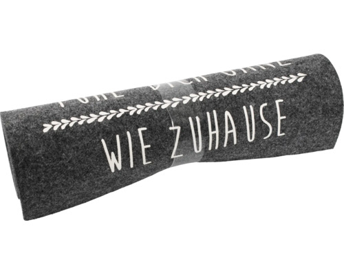 Zusammengerollter grauer Filzläufer mit weißem Schriftzug Fühl dich wie zuhause und Blätterdekor.
