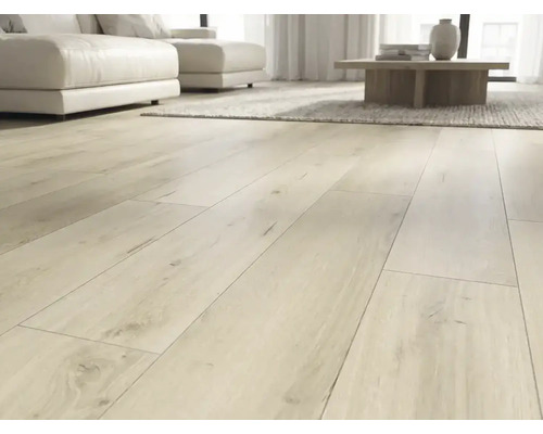 Heller Laminatboden in Eichenoptik als Landhausdiele verlegt in einem modernen, lichtdurchfluteten Wohnzimmer mit weißem Sofa.
