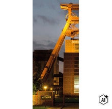 Das beleuchtete Fördergerüst der Zeche Zollverein in Essen bei Dämmerung. (Image AI modified or generated)