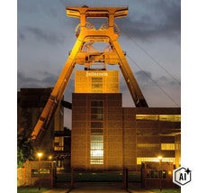 Beleuchteter Förderturm der Zeche Zollverein in Essen bei Dämmerung mit dem beleuchteten Schriftzug Zollverein. (Image AI modified or generated)