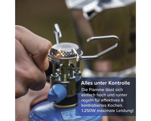 Person zündet einen kompakten Gaskocher mit einer 1250 Watt Leistung für mobiles Kochen an.