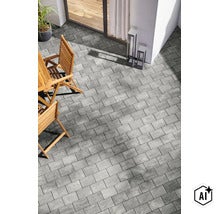 Eine moderne Terrasse mit rechteckigen Pflastersteinen, ausgestattet mit hölzernen Gartenstühlen und dekorativen Außenleuchten vor einer Hausfassade. (Image AI modified or generated)