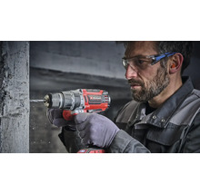 Handwerker mit Einhell Akku Schlagbohrschrauber beim Bohren in eine Betonwand mit Schutzbrille und Gehörschutz.