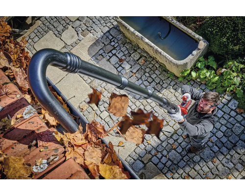 Mann reinigt eine Dachrinne mit einem Akku Laubsaugeraufsatz für Dachrinnen vom Boden aus.