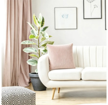 Modernes Wohnzimmer mit weißem Sofa, geripptem Kissen, Zimmerpflanze und Vorhängen in einer hellen Einrichtung.