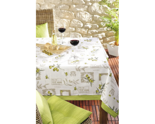 Tischdecke mit Olivenmotiv auf einem gedeckten Gartentisch mit Weingläsern und Oliven auf einer Terrasse.